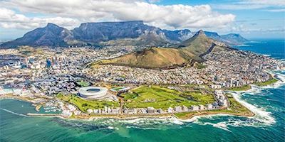 Aerial shot of the city of Capetown with water in front and mountains in back.