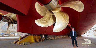 Tor Hagen standing underneath a gold rotar on a Viking Ocean Ship being built.